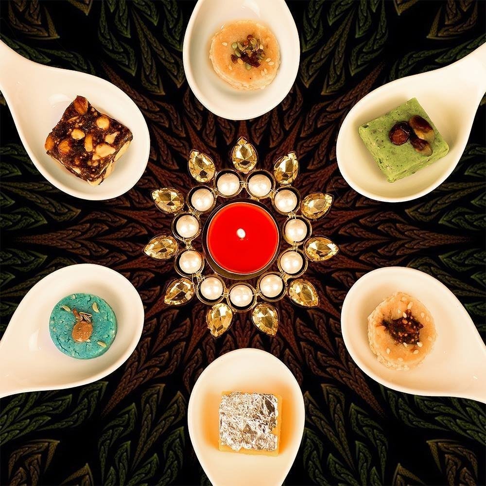 A festive platter of Indian sweets (mithai) arranged around a diya from Punjab Grill