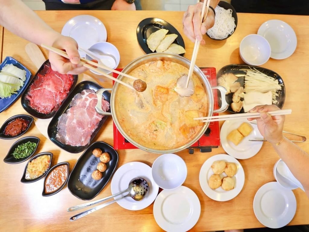Overhead view of a bustling laksa steamboat meal at San Laksa Steamboat