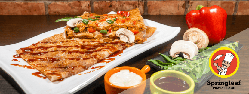 Savory prata dish from Springleaf Prata Place with dipping sauces, mushrooms, and bell pepper, against a brick wall background
