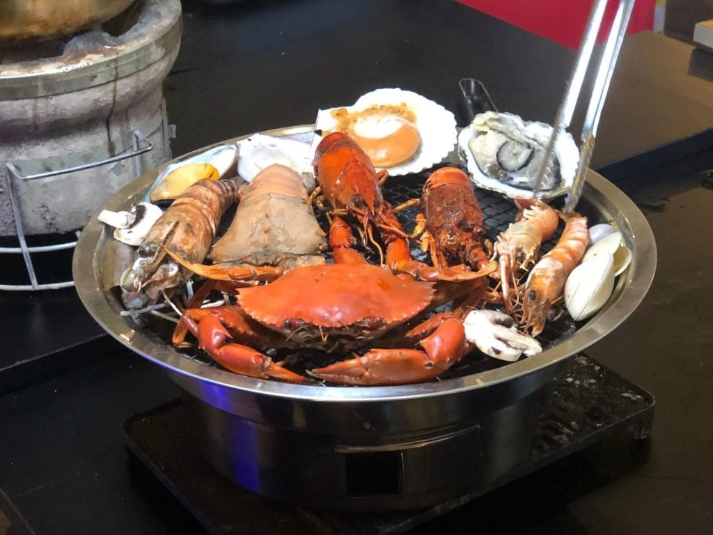 Close-up of a round barbecue grill at The Three Peacocks, laden with an assortment of seafood