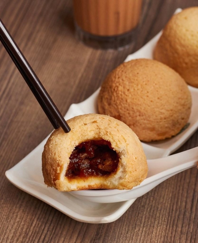 Tim Ho Wan's famous baked BBQ pork buns being opened with chopsticks