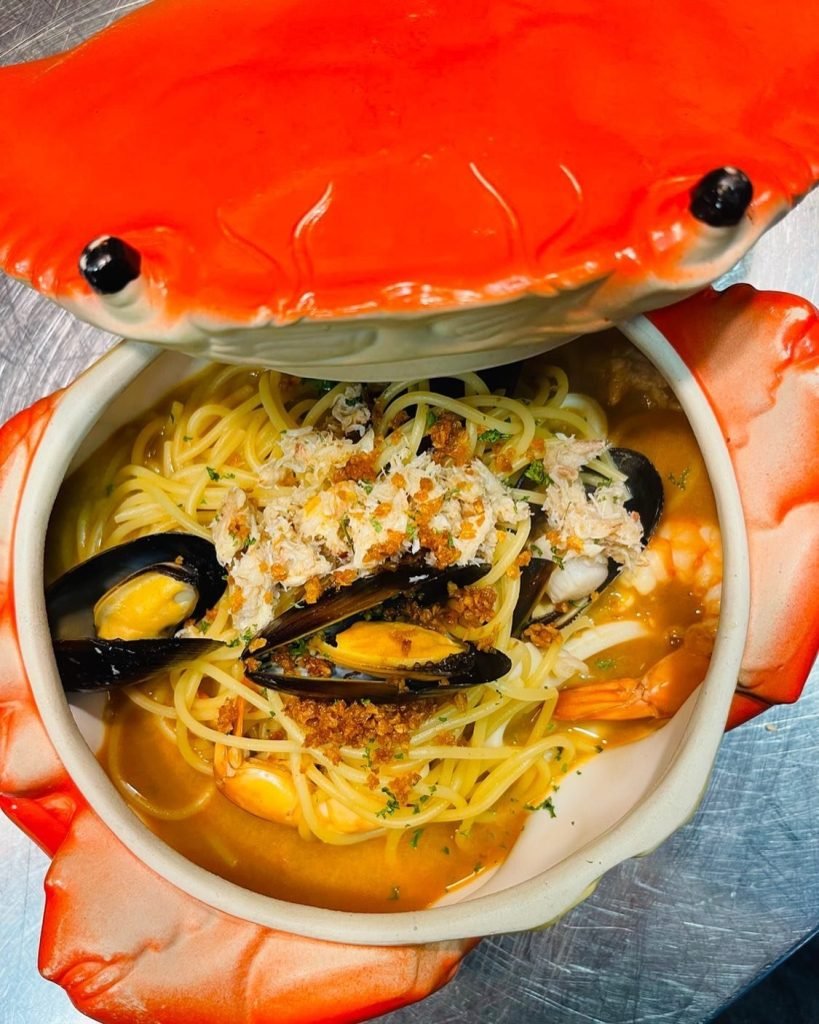 Seafood spaghetti with mussels, shrimp, and crab meat served in a unique bright red crab-shaped lidded bowl at 5 Senses Bistro