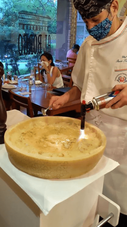Chef at Al Borgo flaming a large cheese wheel with a blowtorch