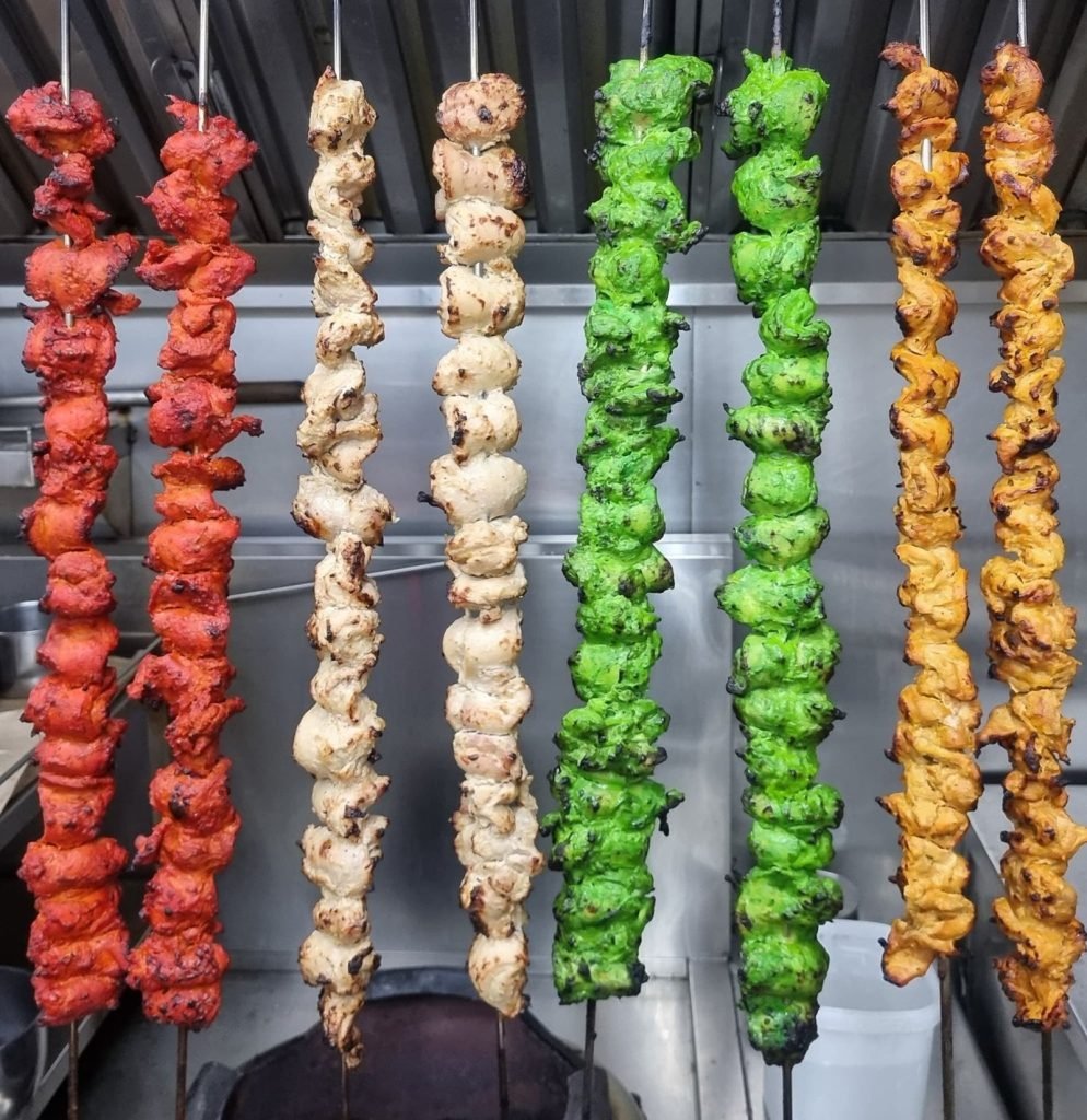 A variety of colorful marinated chicken tikka skewers