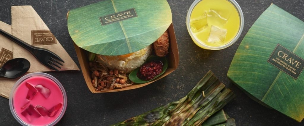 A CRAVE Nasi Lemak takeaway meal spread on a dark surface
