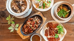Overhead flat lay of a spread of various Chinese dishes on a wooden table