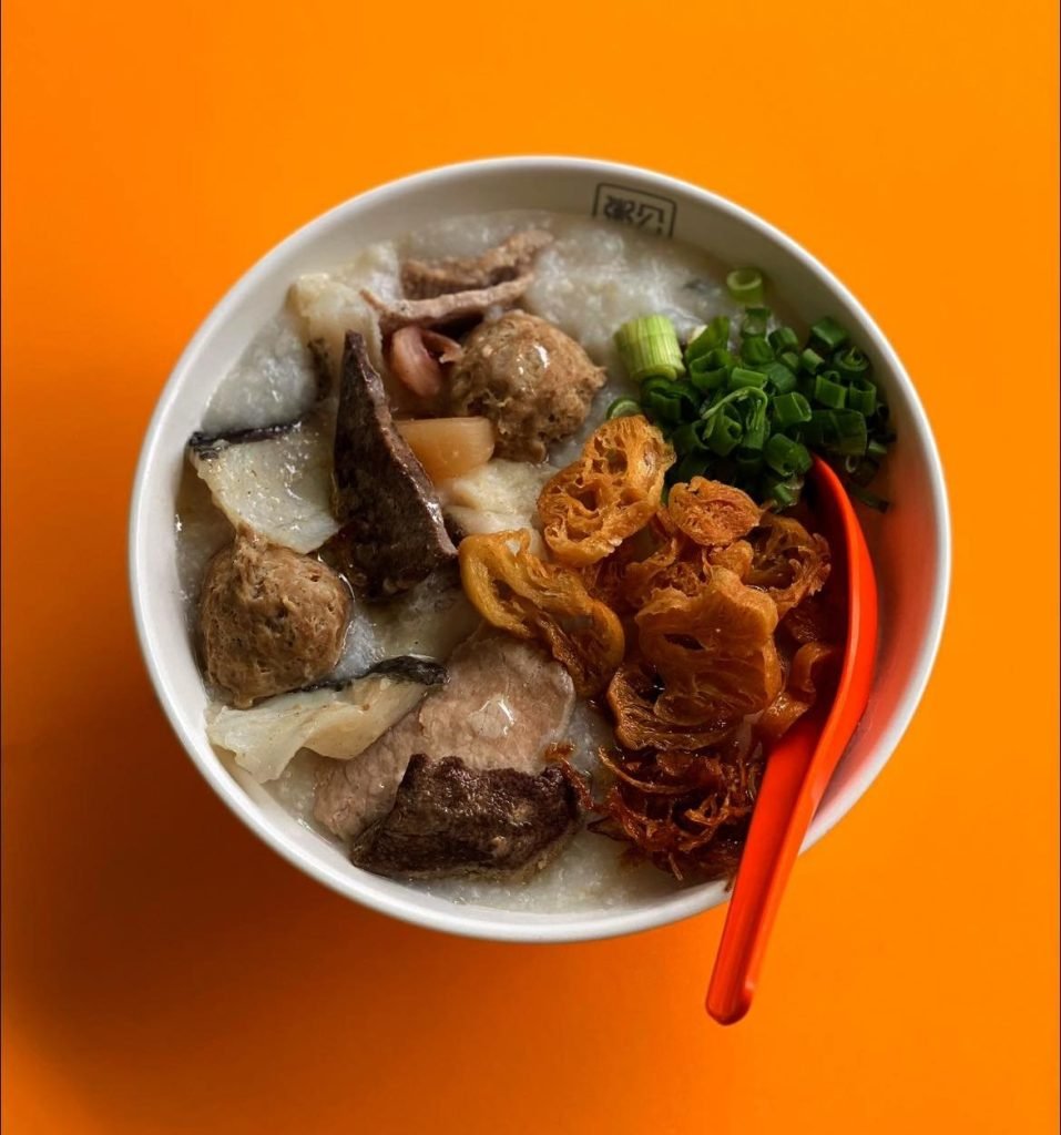 Duke of Congee's hearty rice porridge featuring an assortment of toppings including fish, meatballs, liver, crispy fried dough, and fresh spring onions.