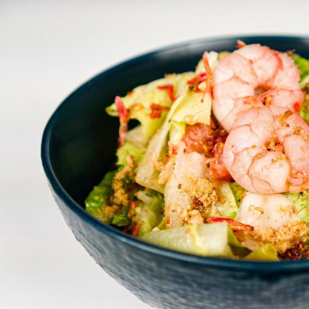 Close-up of a prawn salad from EagleWings Loft, served in a dark textured bowl against a white background
