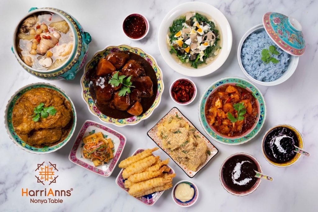A vibrant overhead shot of a Nonya food spread from HarriAnns Nonya Table on a white marble surface.