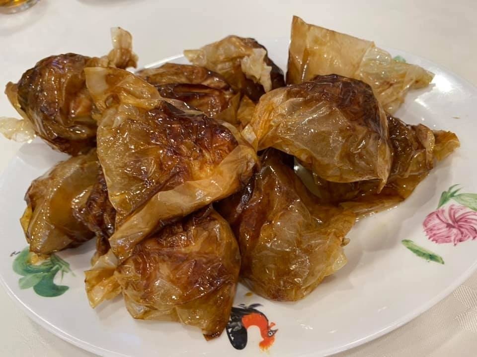 A serving of deep-fried, golden-brown beancurd skin parcels from Hillman 99 Restaurant, piled on a white ceramic plate decorated with a rooster and floral motif