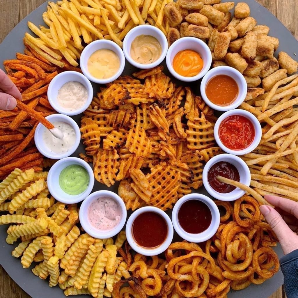 A large, circular grey platter from Martin Zwerts Friture, artfully arranged with a wide variety of fried potato snacks