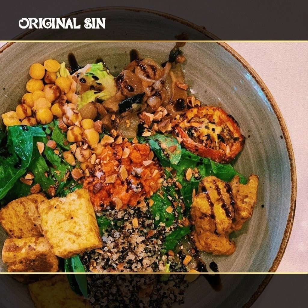 Original Sin Restaurant's signature vegetarian bowl, packed with fresh greens, quinoa, tofu, chickpeas, roasted vegetables, nuts, and a balsamic glaze