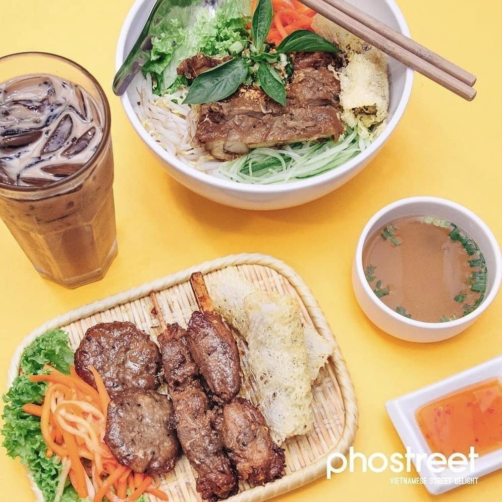 Pho Street Galaxis Vietnamese street food: A Bún thịt nướng set with grilled pork vermicelli bowl, a side platter of grilled meats and spring roll, iced coffee, soup, and dipping sauce, viewed from above.