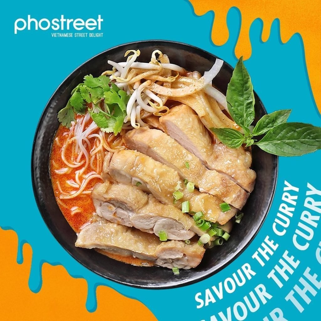 Pho Street's curry noodle dish: a black bowl filled with red curry broth, rice noodles, sliced chicken, bean sprouts, and fresh herbs, against a colorful graphic backdrop