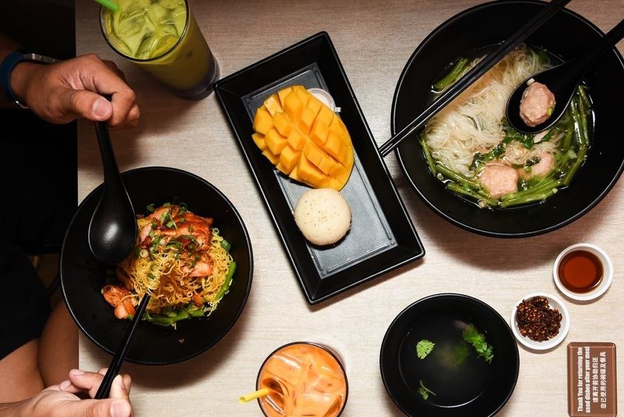 A spread of Thai food on a light wooden table,