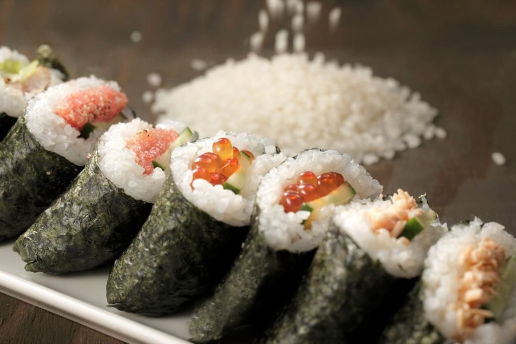 A close-up of various Japanese maki sushi rolls presented on a white plate