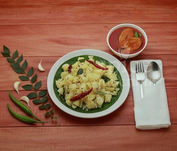 Authentic Kerala cuisine from Spice Junction: a plate of boiled and seasoned tapioca (kappa) on a banana leaf, alongside a bowl of spicy fish curry