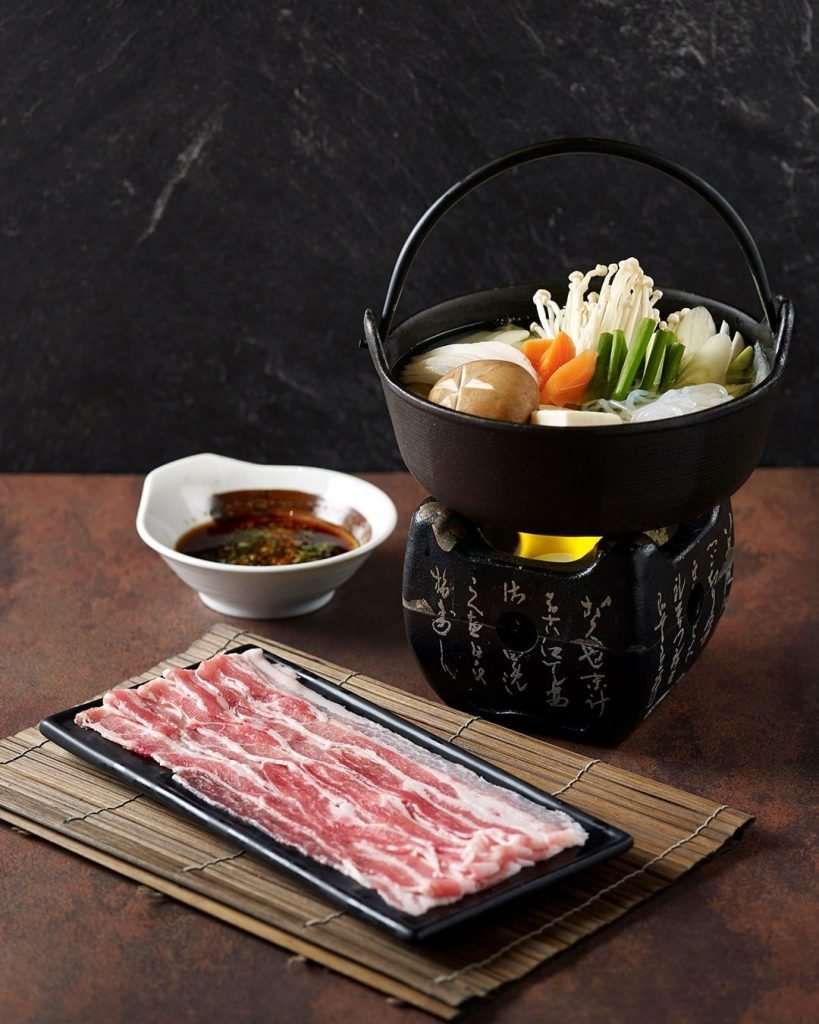 Japanese Nabe or Shabu-shabu set with a hot pot of vegetables, sliced raw meat, and dipping sauce