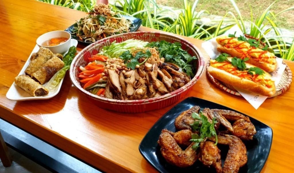 Spread of Vietnamese dishes: Bun Thit Nuong, Banh Mi, spring rolls, chicken wings, and salad.