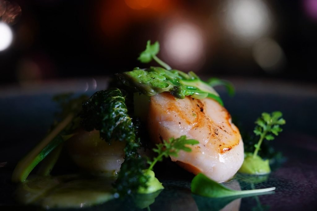 Close-up of a seared scallop dish with green garnishes