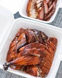 Chopped Chinese roasted chicken with crispy skin in a white styrofoam takeaway container