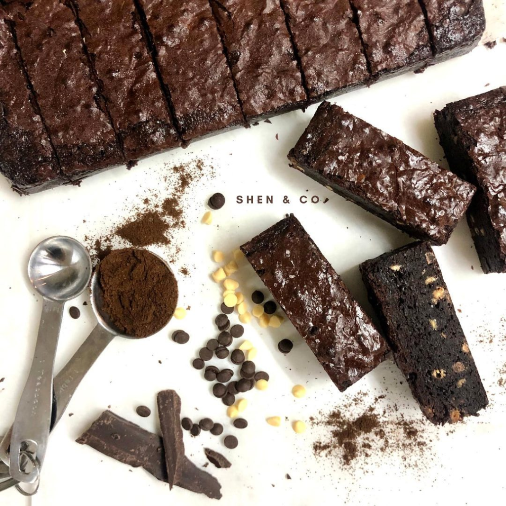 Overhead shot of a pan of Shen&Co sliced dark chocolate brownies, with several individual brownie bars, scattered dark and white chocolate chips
