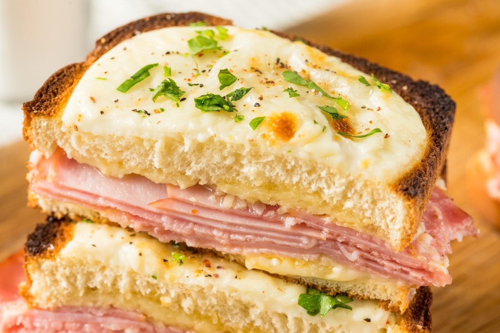 A close-up of a Croque Monsieur sandwich, cut and stacked to show layers of ham