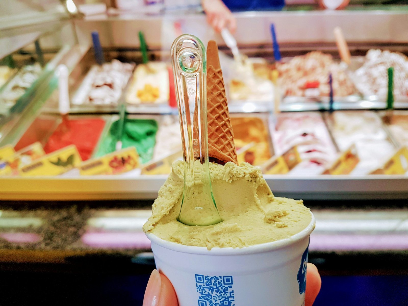 A close-up of a hand holding a cup of creamy Mao Shan Wang durian ice cream