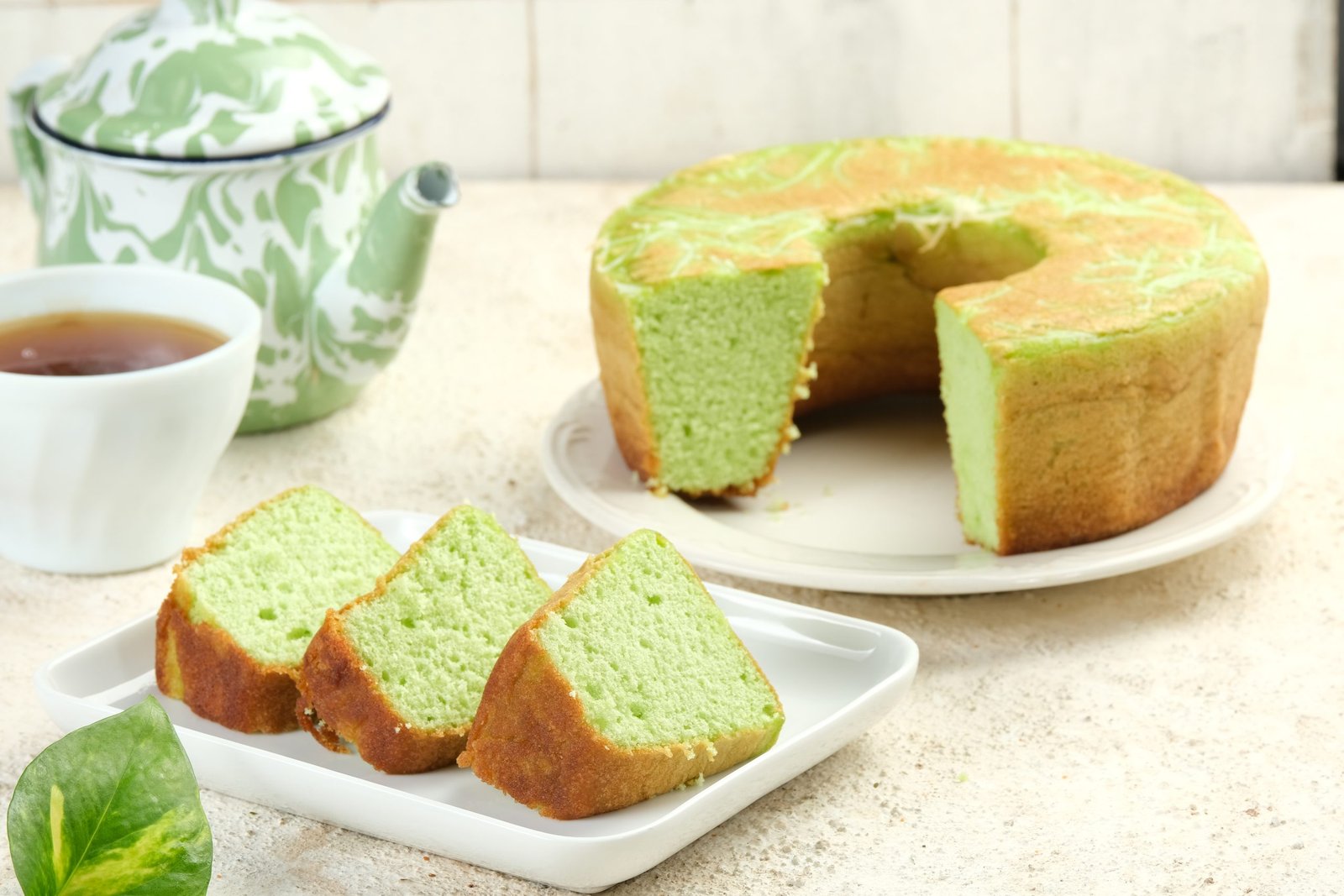 Slices of light green pandan chiffon cake are served on a white plate