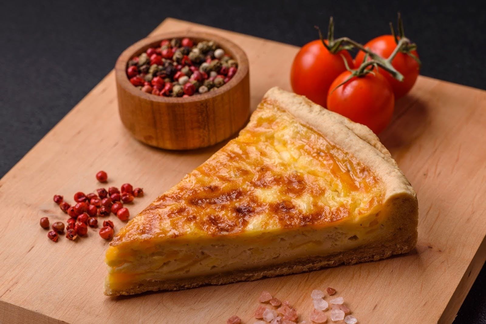 A slice of freshly baked Quiche Lorraine on a wooden board