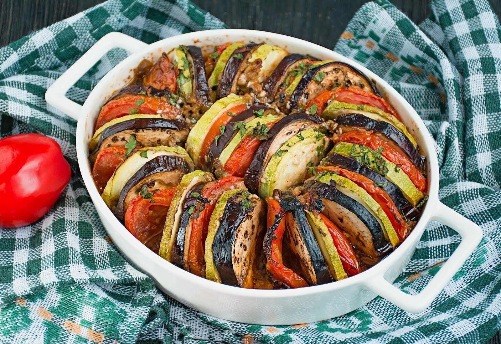 A white oval baking dish filled with freshly baked ratatouille.