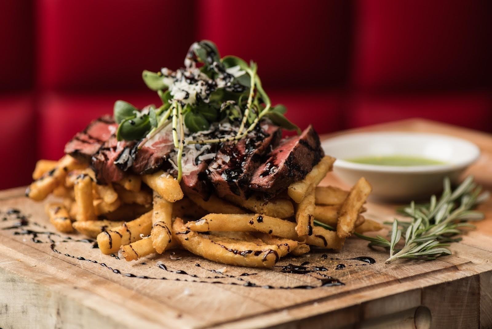 A gourmet dish of steak frites served on a wooden board