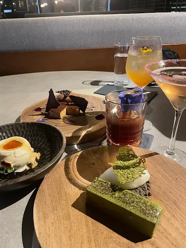 spread of modern desserts and craft cocktails on a grey table
