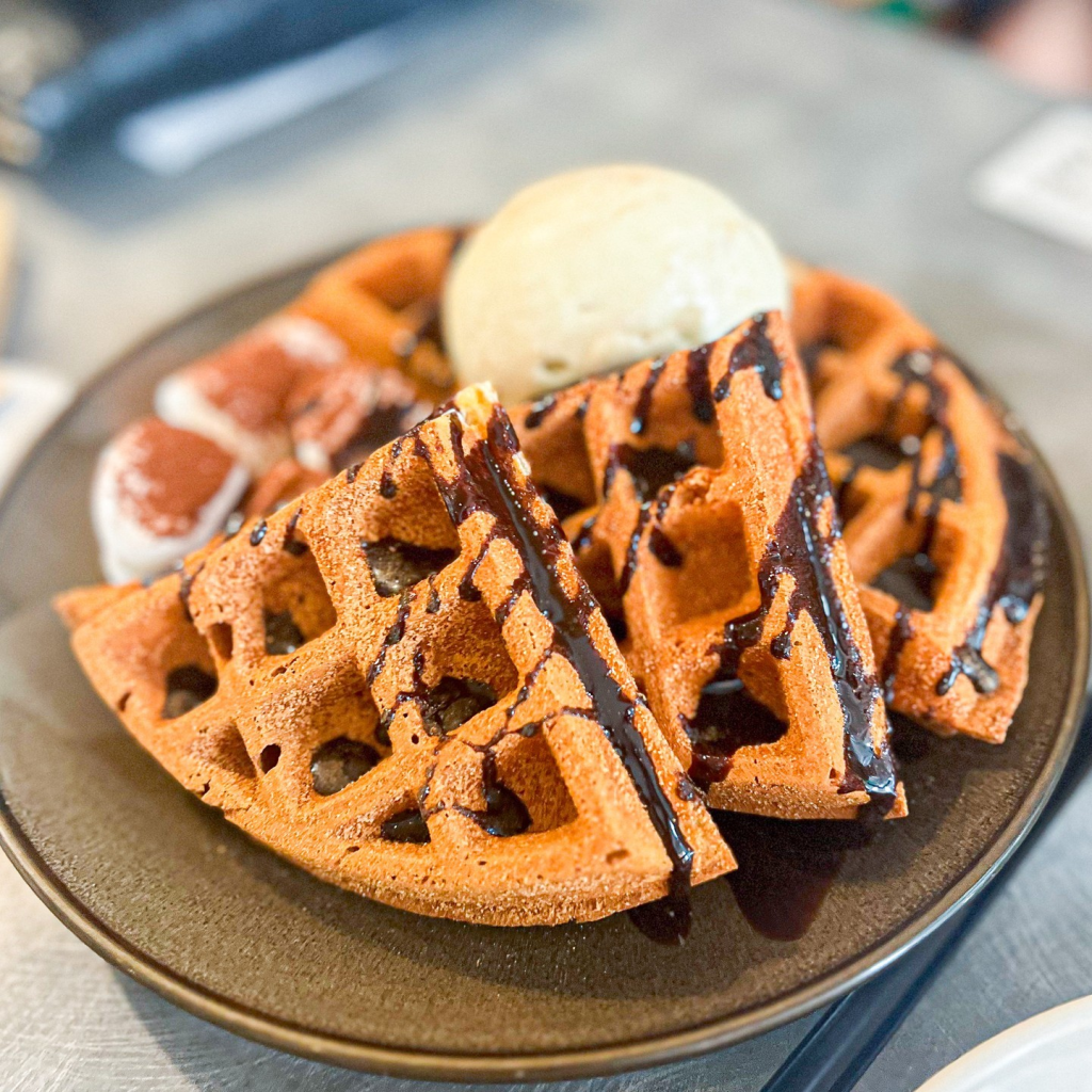 A plate of golden-brown waffles from Three's a Crowd