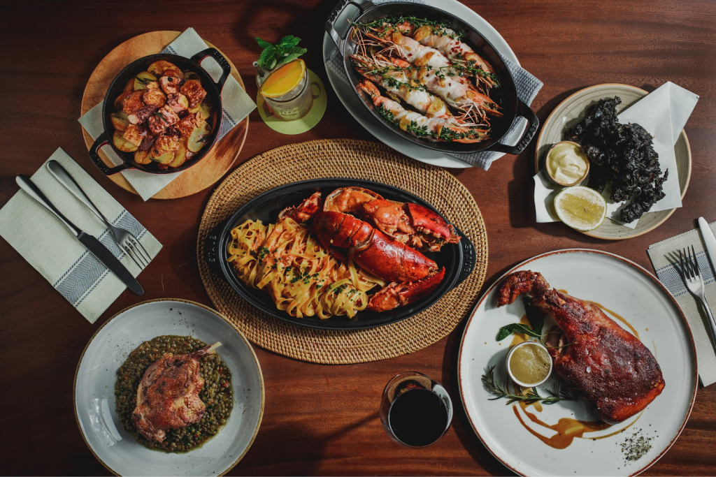 Three Neapolitan-style artisanal pizzas with charred, bubbly crusts served on a marble table with olives, oil, and a lemon water carafe at LINO @ Forum