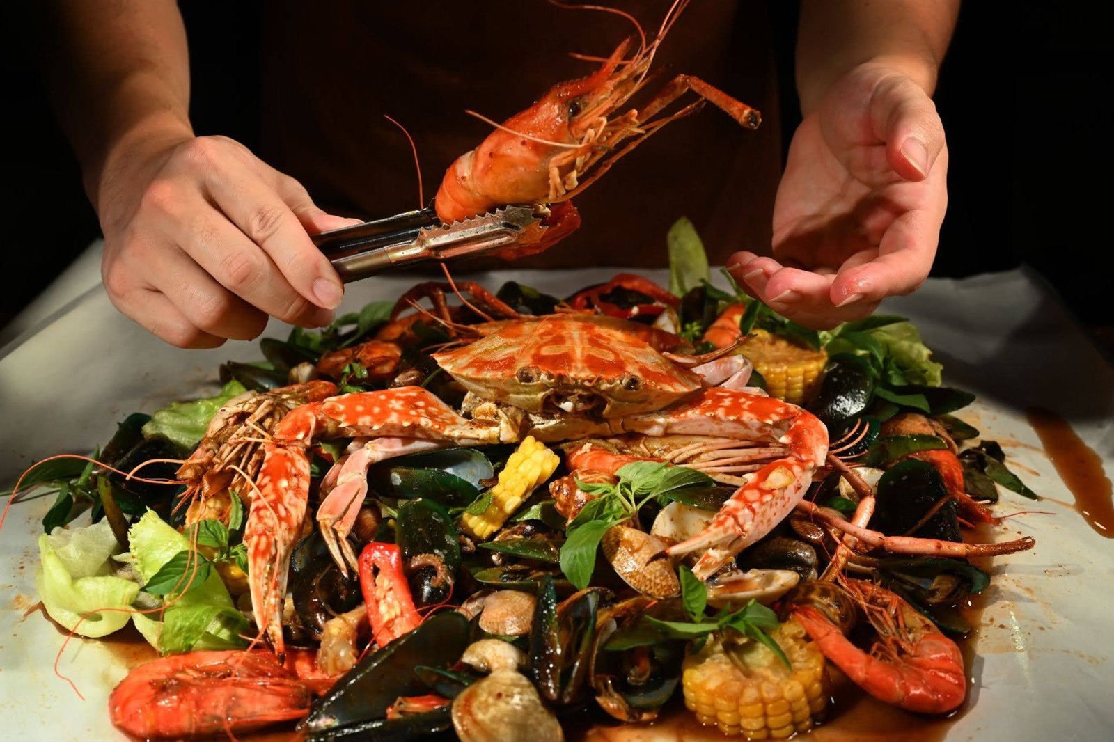 Hands reaching for a spread of dishes at the best halal seafood restaurant in Singapore
