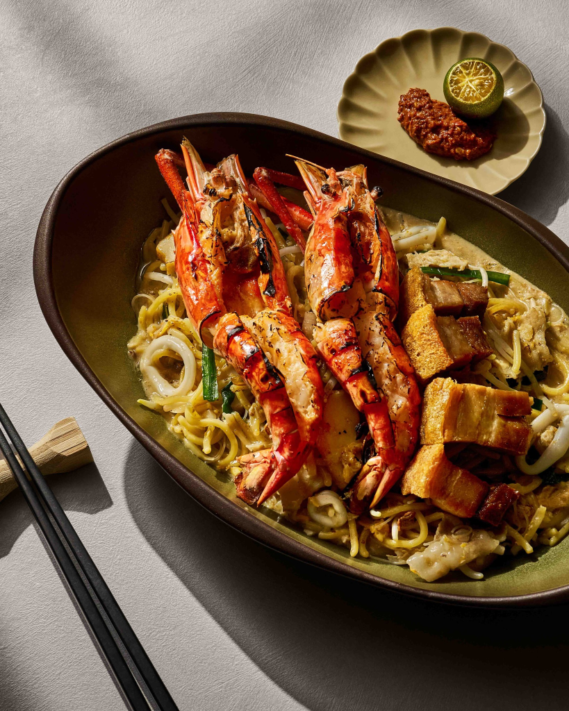Hokkien mee topped with grilled tiger prawns, crispy pork belly, calamansi, and sambal