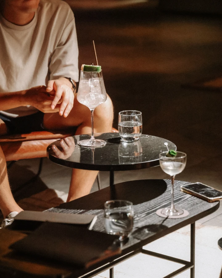 Iced cocktails and glasses of water served on small tables in a hotel lounge