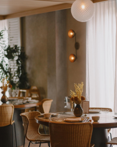 Elegant dining table with woven rattan chairs and floral vase at Po Restaurant